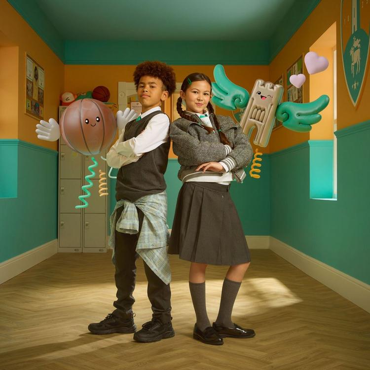 Boy and girl stood back to back wearing school uniform and Clarks school shoes.